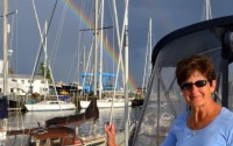 Woman in front of boat with rainbow in the background