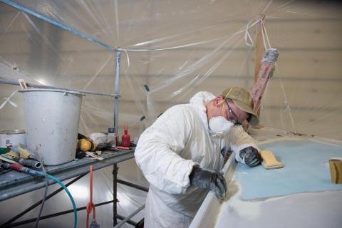 Fiberglass technician repairing damaged boat Fiberglass technician repairing damaged boat